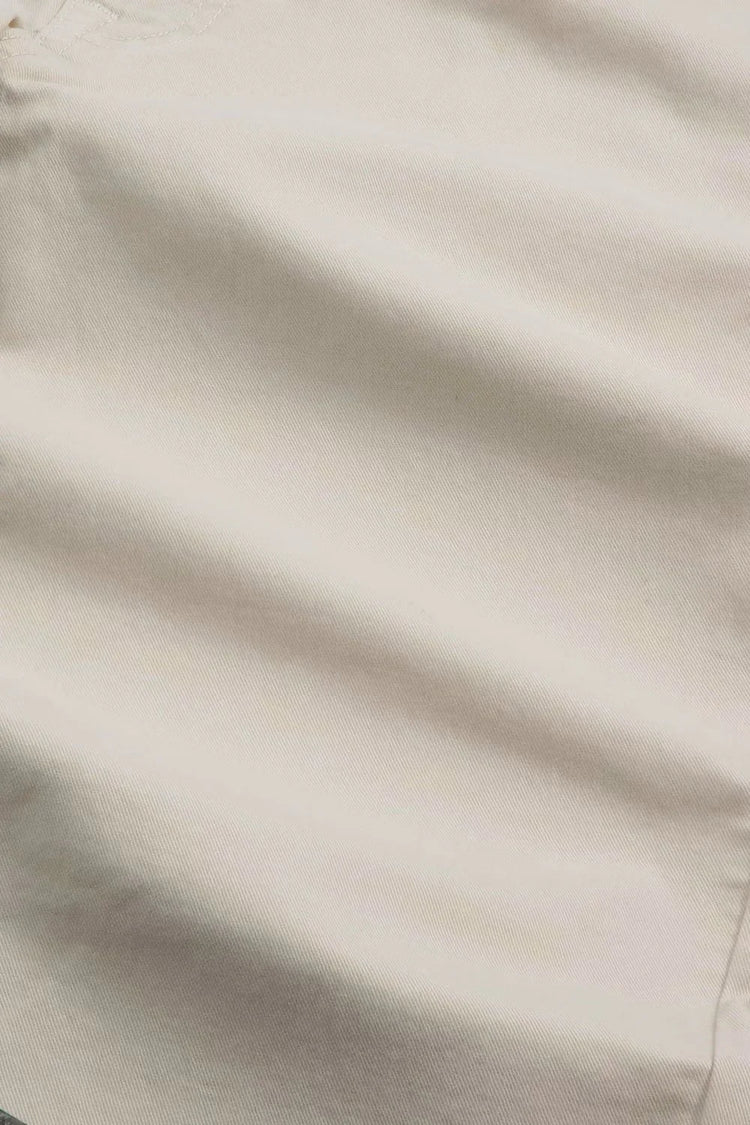 Närbild av beige bomullstyg med synlig söm, herrkläder materialstruktur