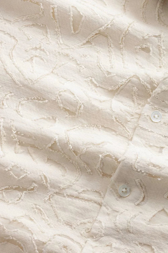 Närbild av beige herrskjorta med strukturmönster och knapp, klassiskt herrmode tyg