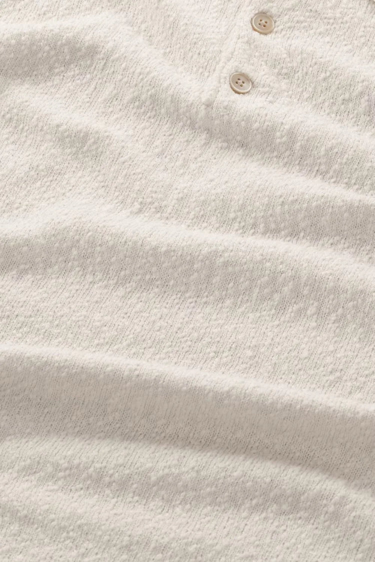 Närbild på beige herrtröja i texturerat tyg med två knappar, klassiskt herrmode.
