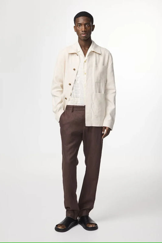Man i beige linnejacka, vit skjorta och bruna byxor, modernt herrmode.