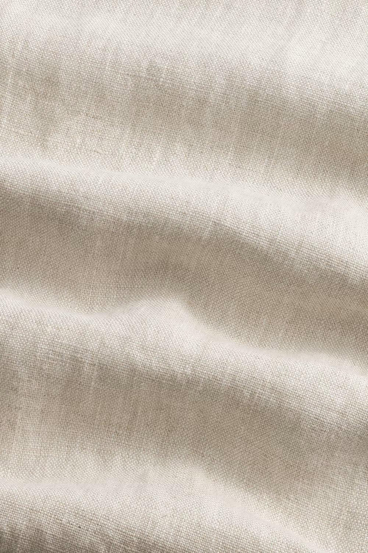 Närbild på beige linnetyg med synlig struktur och mjuka veck, herrkläder material