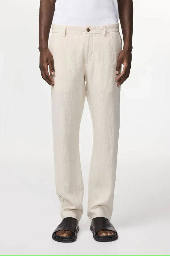 Herrmodell med beige linnabyxor, vit t-shirt och svarta sandaler, klassisk stil