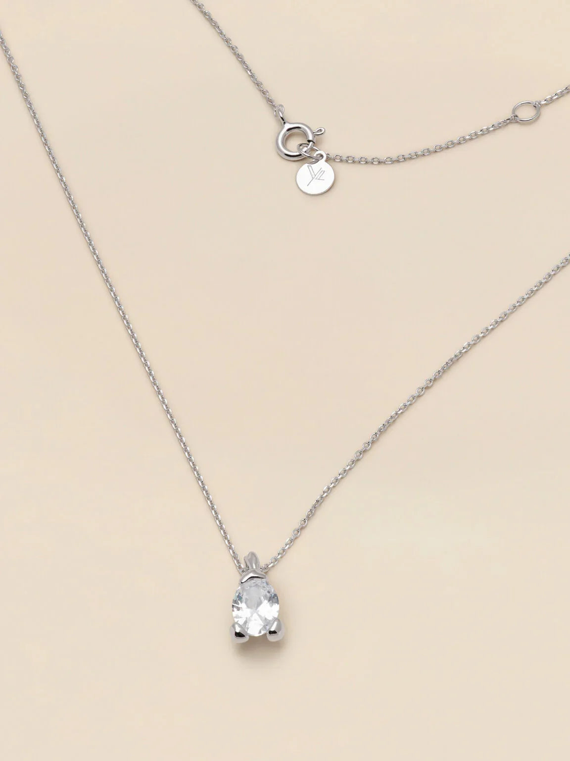 Elegant silverhalsband med gnistrande klar stenberlock på ljus bakgrund