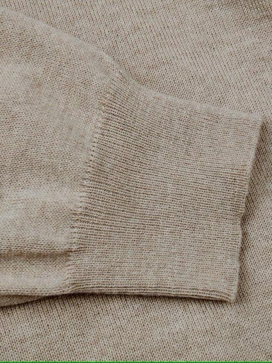 Beige stickad herrtröja med nära bild på ärmslut i ullmix