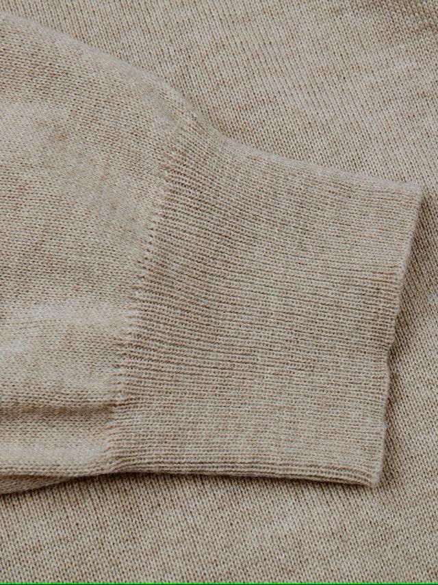 Beige stickad herrtröja med nära bild på ärmslut i ullmix