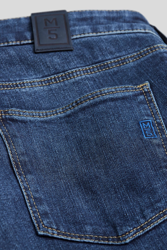 Närbild på bakficka av mörkblå herrjeans med dekorativa sömmar