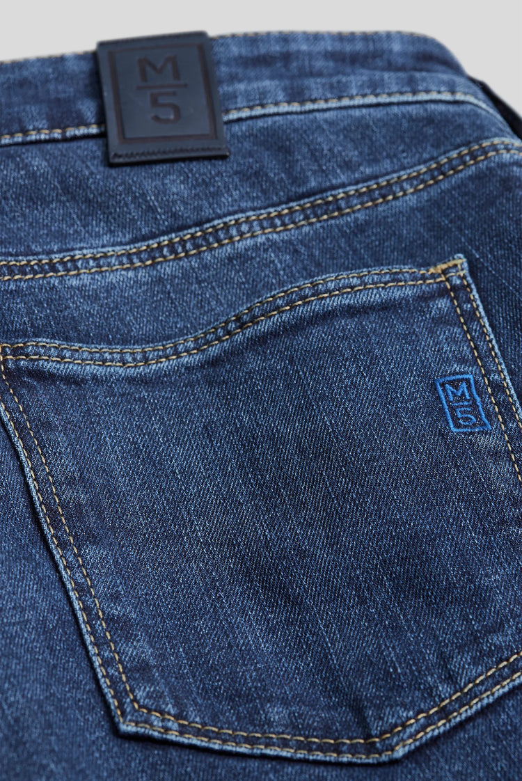 Närbild på bakficka av mörkblå herrjeans med dekorativa sömmar