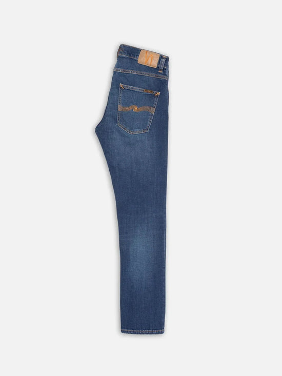 Blå herrjeans i klassisk modell, vikta, med bakficka och gul söm på ljus bakgrund.