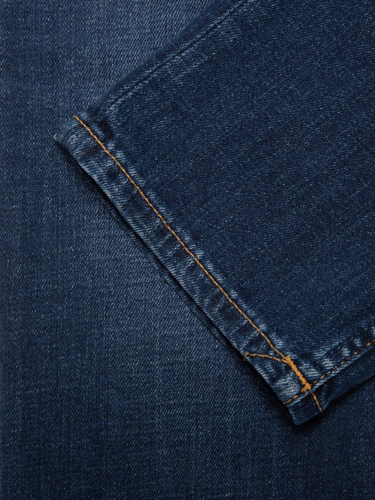 Närbild på mörkblå jeans med orange söm, klassiska herrjeans i denim