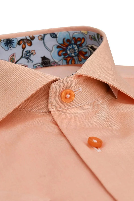 Närbild av persikofärgad skjortkrage med blommigt mönster på insidan, herrmode.