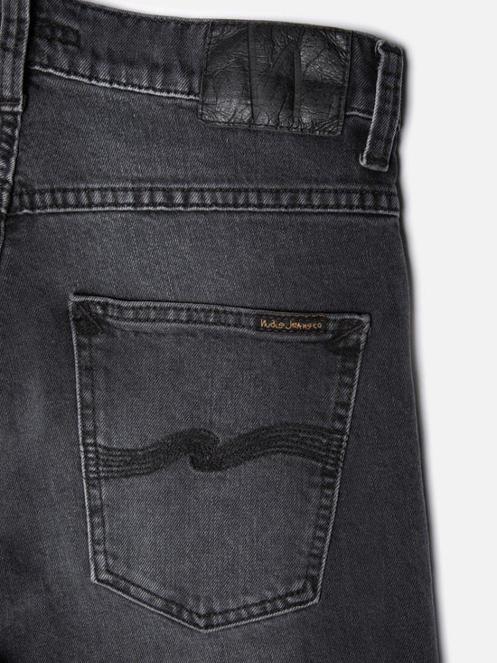 Bakficka av svarta herrjeans i denim med broderad detalj och läderpatch på linningen.