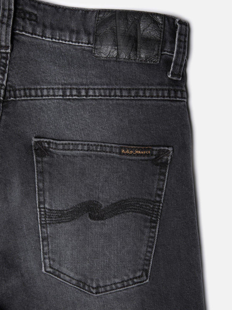Bakficka av svarta herrjeans i denim med broderad detalj och läderpatch på linningen.