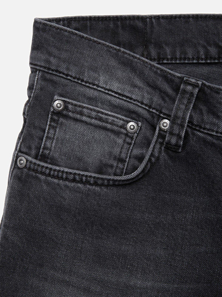 Närbild av svart herrjeans med fickdetaljer och nitar, klassiska herrkläder