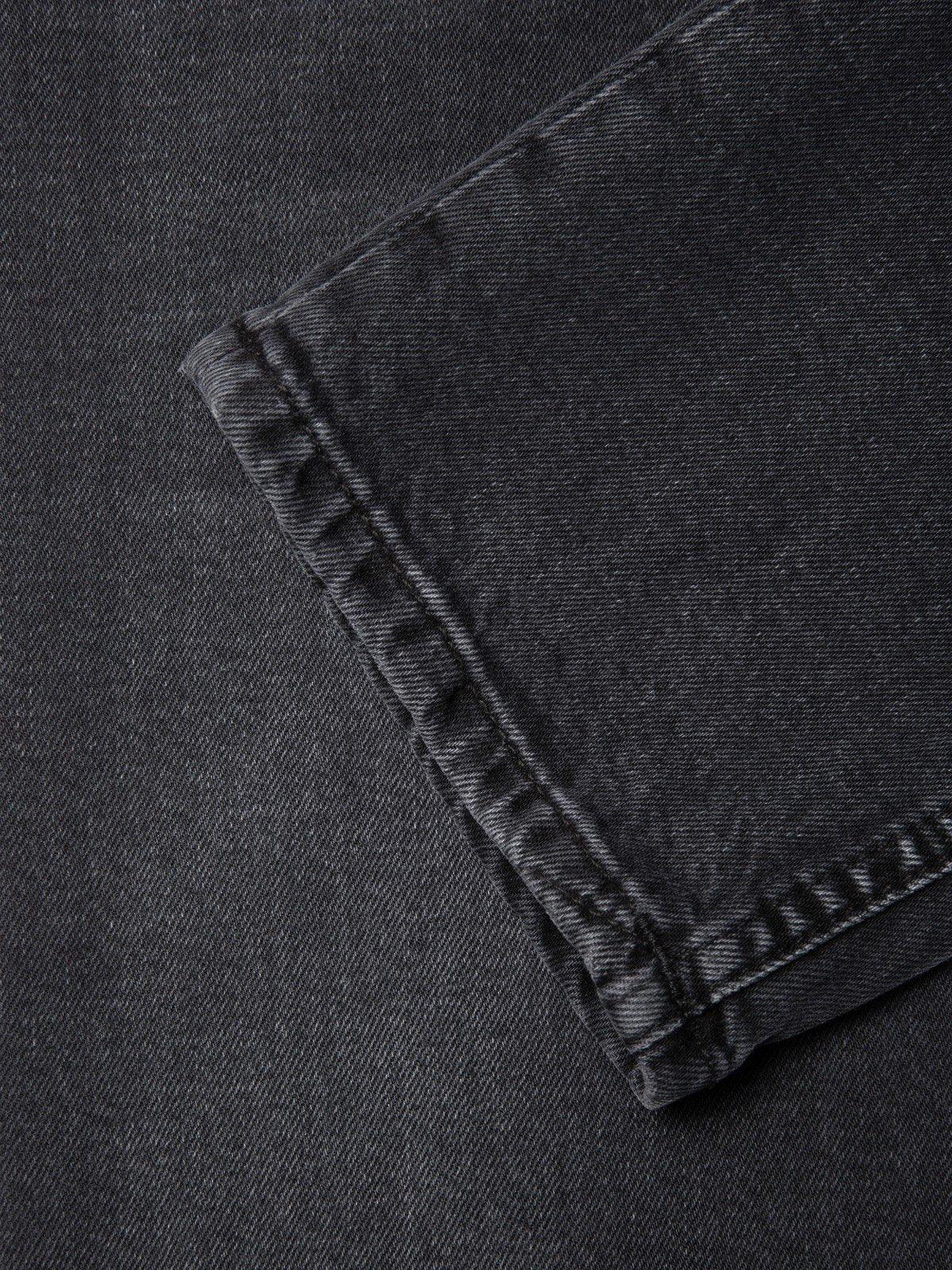 Närbild på benavslut av mörkgrå herrjeans i denim, klassiska herrkläder.