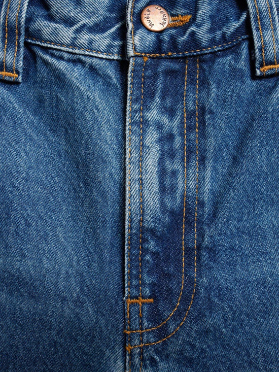 Närbild på blå herrjeans med synliga sömmar och knapp, klassiska denimbyxor