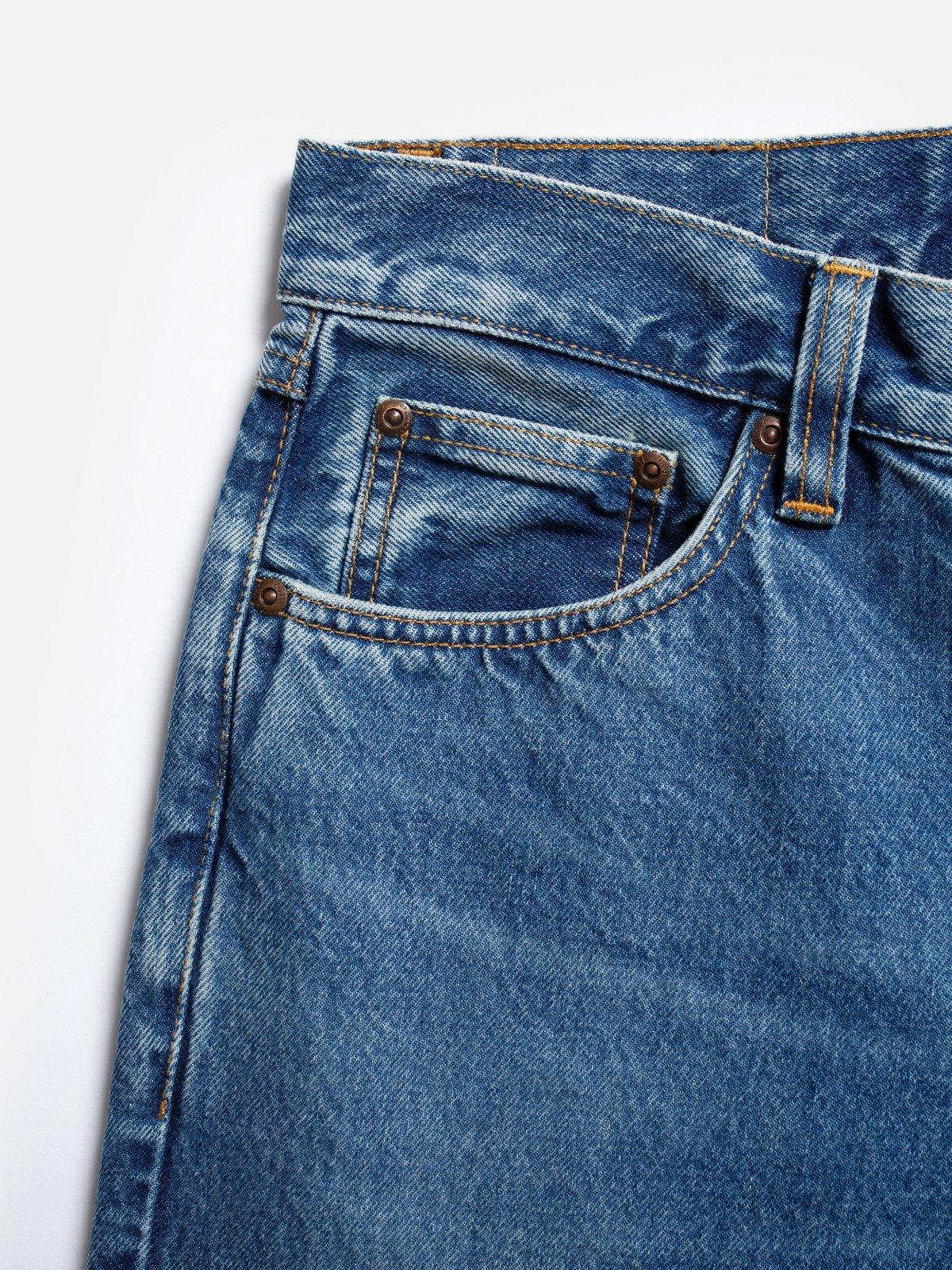Närbild på klassiska herrjeans i blå denim med fickdetaljer och nitar