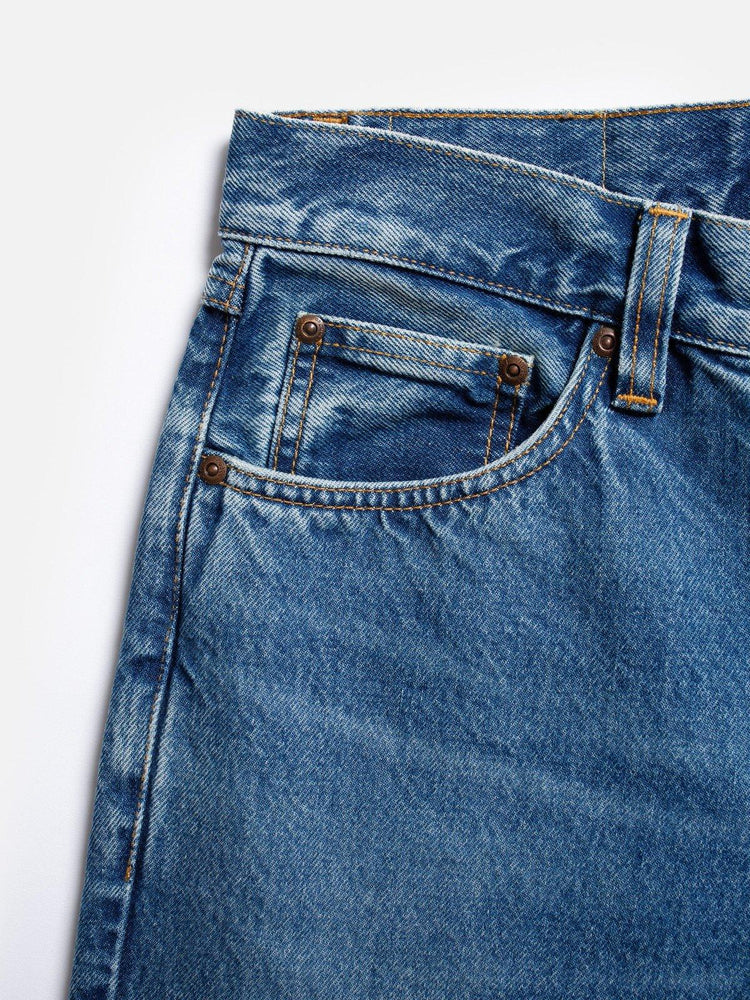 Närbild på klassiska herrjeans i blå denim med fickdetaljer och nitar
