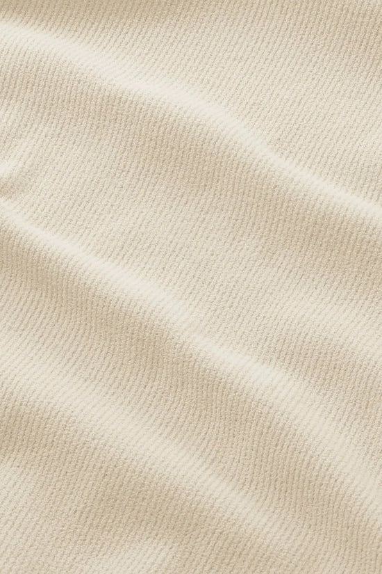 Närbild på beige strukturerat tyg för herrkläder med subtil ribbad yta