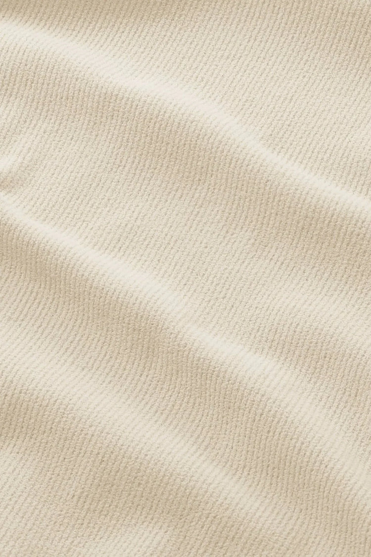 Närbild på beige strukturerat tyg för herrkläder med subtil ribbad yta