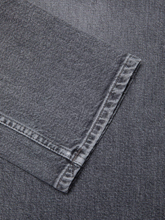 Närbild på grå denim byxben med tydliga sömmar, herrjeans, klassisk stil.