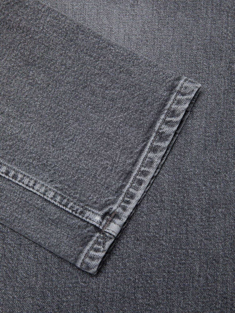 Närbild på grå denim byxben med tydliga sömmar, herrjeans, klassisk stil.