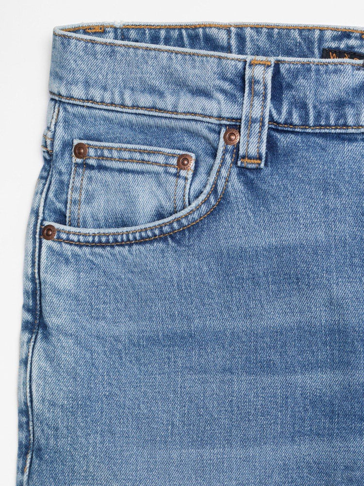 Detaljbild av blå jeans med klassisk femficksdesign och kopparnit, herrmode.