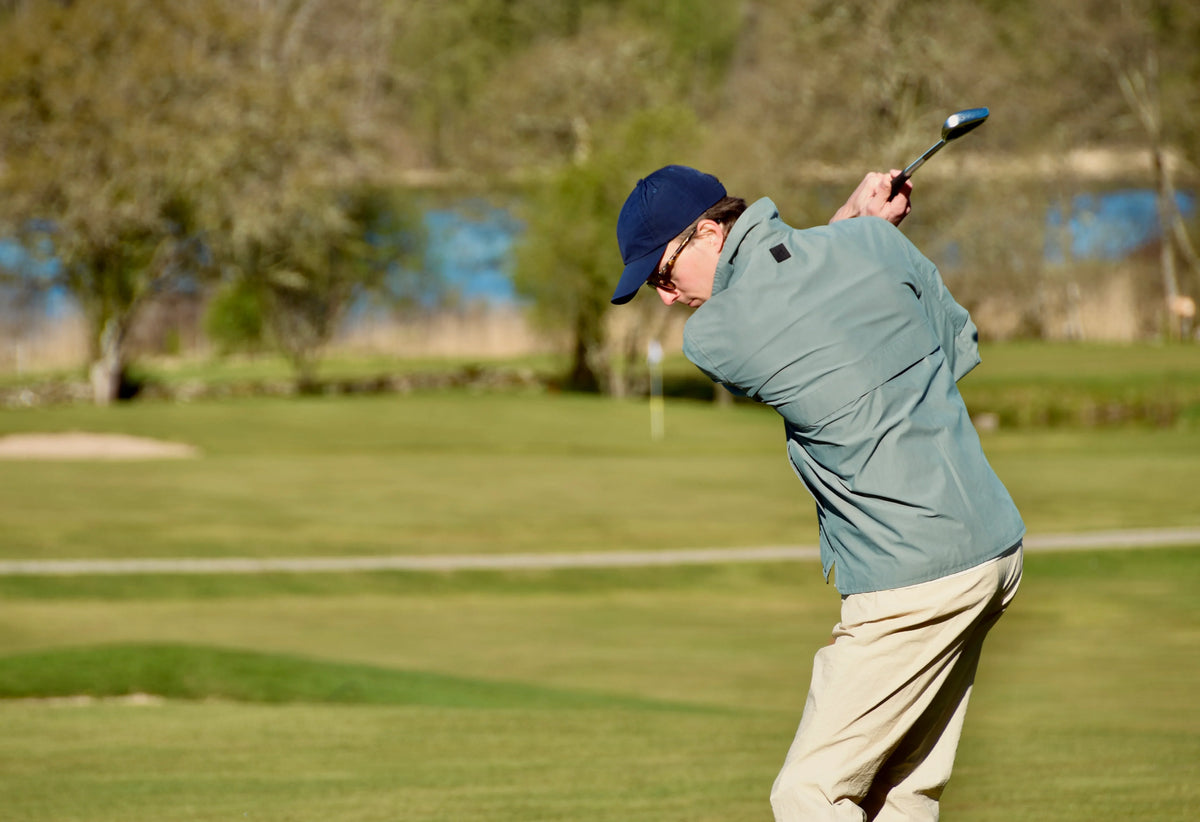 Blå golfmössa herr, ljusgrön golfjacka och beige golfbyxor