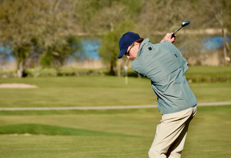 Blå golfmössa herr, ljusgrön golfjacka och beige golfbyxor