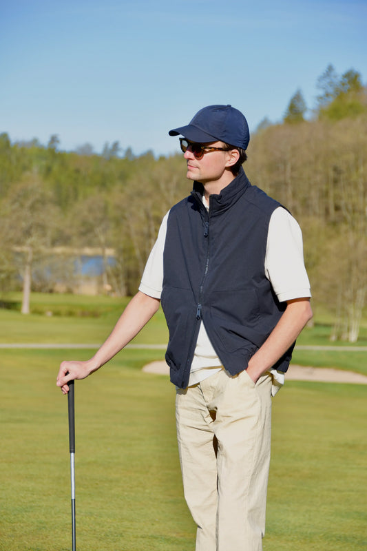 Mörkblå golfväst herr med dragkedja, vit skjorta och beige byxor