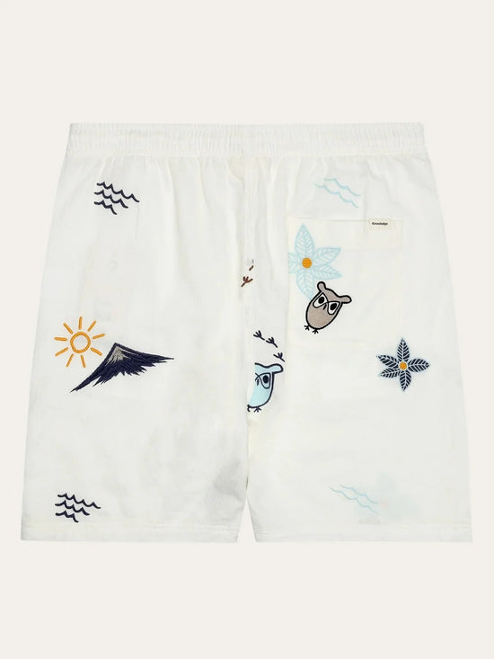 Vita herrshorts med broderade motiv av ugglor, blommor, vågor och solen, elastisk midja