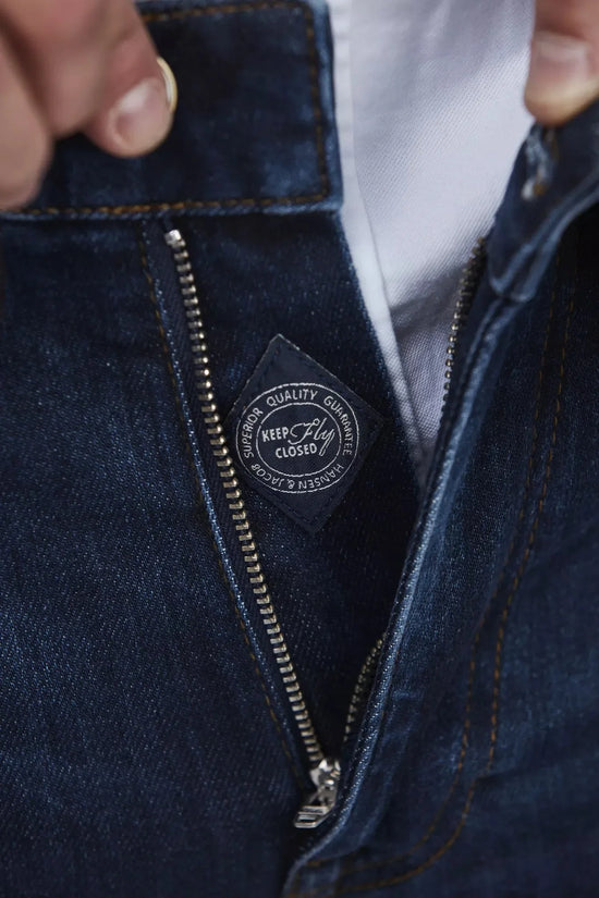 Närbild på blå denimbyxa med dragkedja och synliga detaljer, herrkläder.