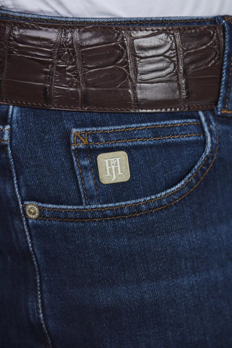 Detalj av herrjeans i mörkblå denim med brun läderbälte och fickdetalj