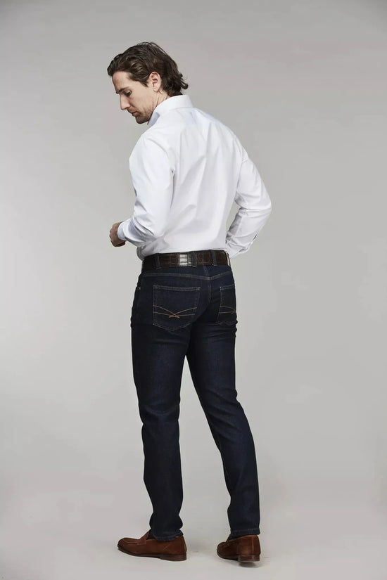 Herr i vit skjorta och mörkblå denimbyxor, bakifrån, mot ljus bakgrund