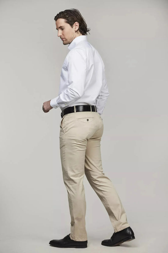 Herr i beige chinos och vit skjorta, svart bälte, klassisk stil, neutral bakgrund