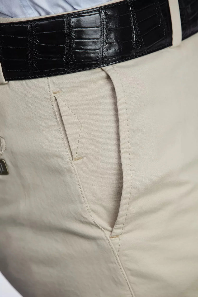 Detaljbild av beige herrchinos med hög stretch och svart läderbälte