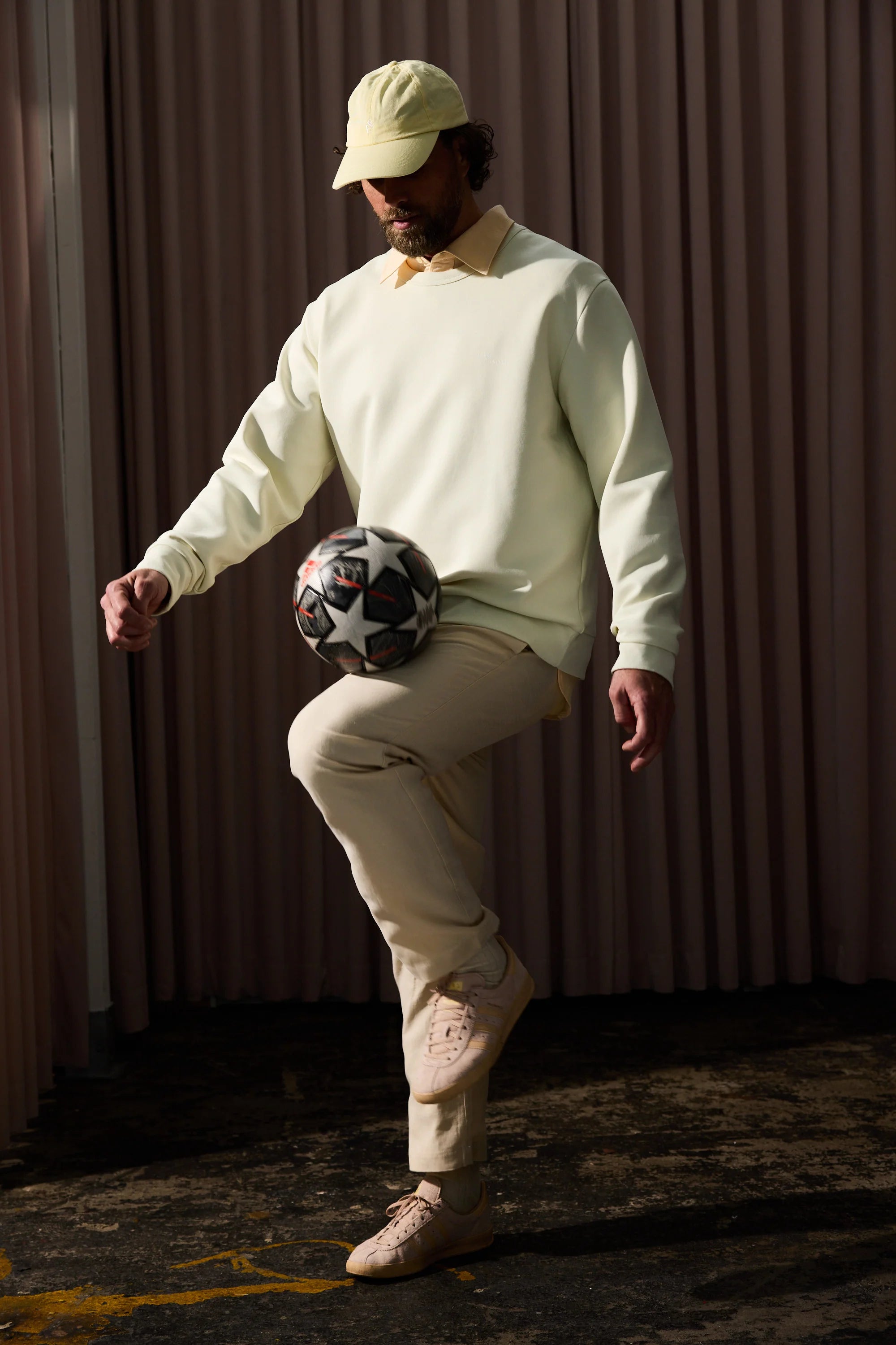 Ljusgul sweatshirt herr, beigefärgade byxor, beige keps, sneakers