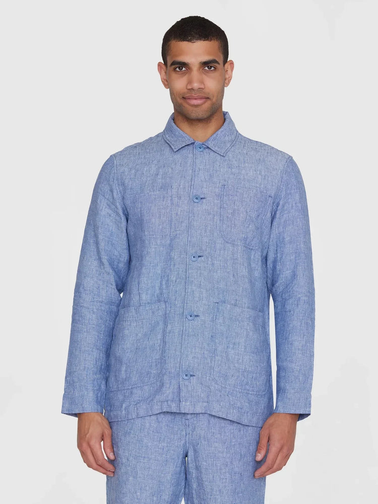 Man i blå linneskjorta, overshirt med knappar och fickor, mot vit bakgrund.