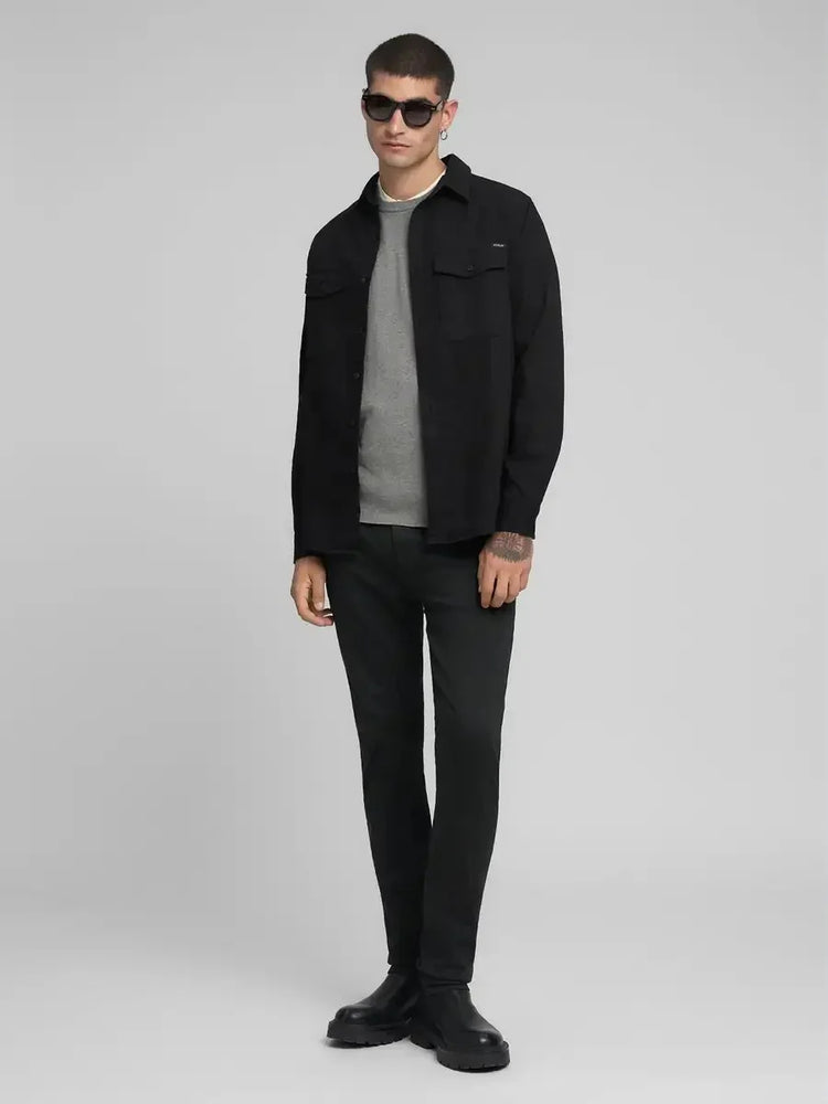 Man i svarta jeans, grå tröja och svart skjortjacka, moderna herrkläder, helkroppsbild.