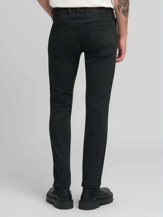 Svarta herrjeans med smal passform, bakfickor, bälte och svarta läderskor.