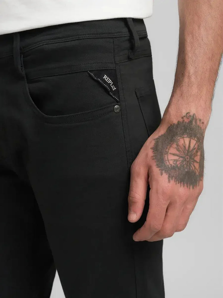 Svarta jeans för herr, närbild på ficka med Replay-logotyp och tatuering på handen