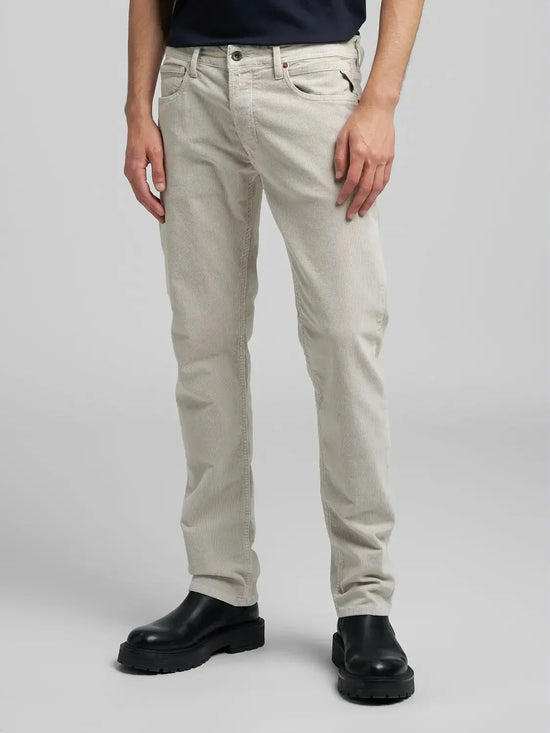 Herrmodell med ljusa raka jeans och svarta boots mot grå bakgrund