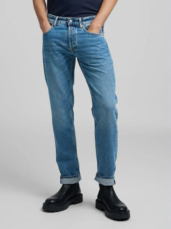 Herr i blå raka jeans och svarta boots, klassisk stil, neutral bakgrund
