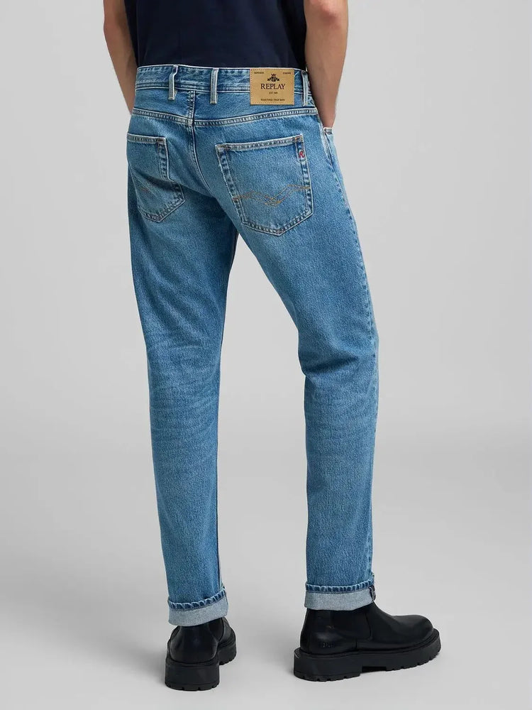 Herrmodell i ljusblå jeans med uppvikta benslut och svarta skor, bakifrån.