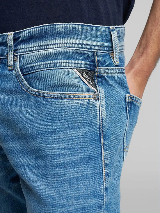 Närbild på klassiska blå herrjeans med hand i fickan, tydlig sömnad och fickdetaljer.