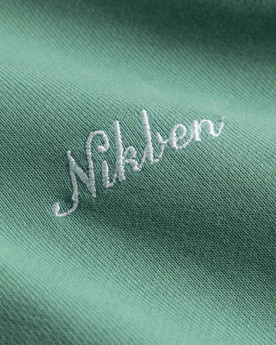 Mintgrön hoodie med vit broderad logo, närbild på herrkläder i bomullstyg