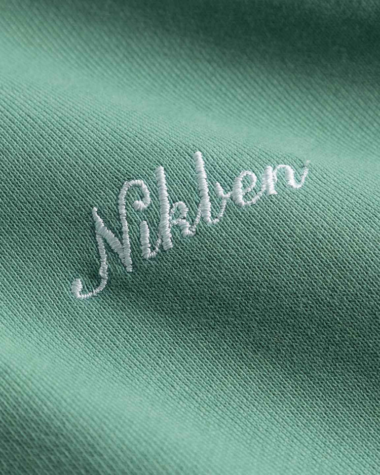 Mintgrön hoodie med vit broderad logo, närbild på herrkläder i bomullstyg