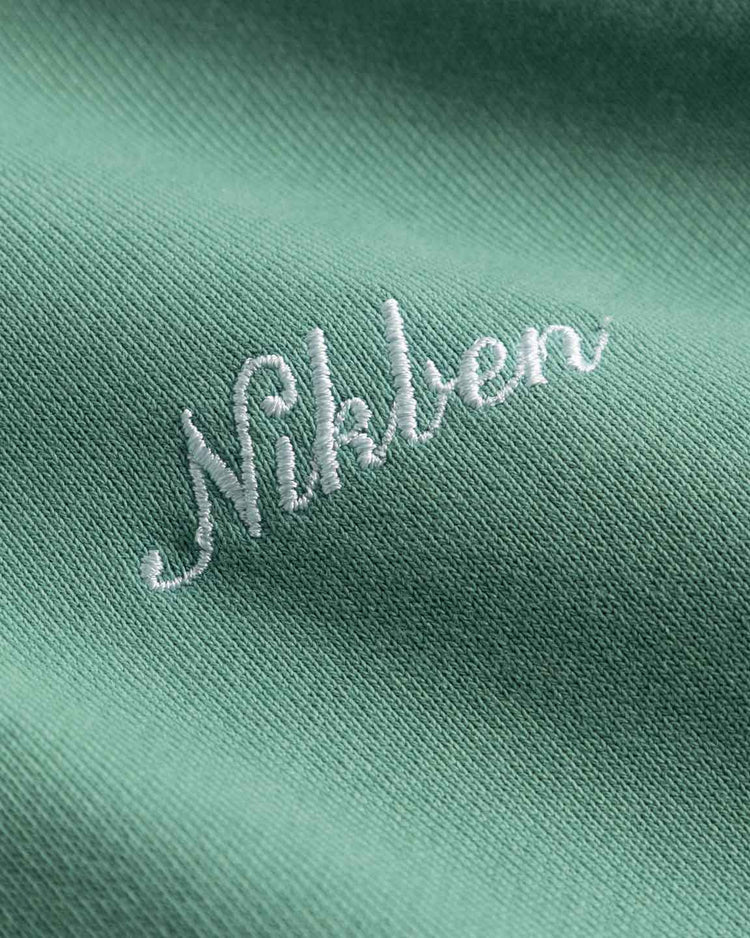 Mintgrön hoodie med vit broderad logo, närbild på herrkläder i bomullstyg