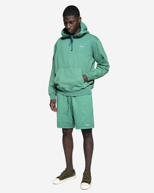 Man i grön hoodie och matchande shorts, avslappnad herrklädstil, vit bakgrund