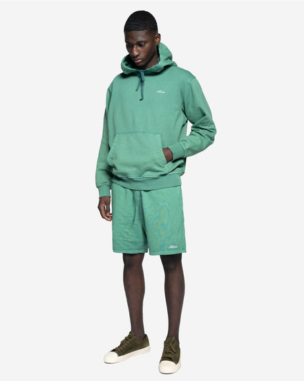 Man i grön hoodie och matchande shorts, avslappnad herrklädstil, vit bakgrund