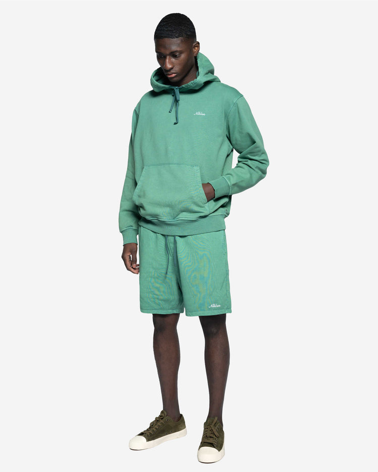 Man i grön hoodie och matchande shorts, avslappnad herrklädstil, vit bakgrund